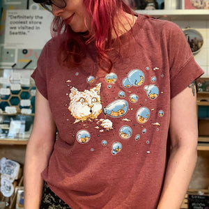 Person wearing a red t-shirt with a cat graphic in a store setting