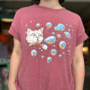 Person wearing a maroon t-shirt with a cartoon cat design. There is a cloud in the shape of a large cat head that is blowing bubbles. Inside the bubbles are tiny kittens.