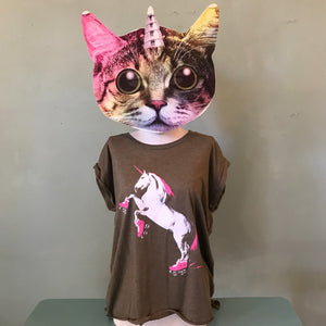Person wearing a cat mask with a colorful unicorn horn and a brown shirt with a roller skating unicorn design in neon pink and white.
