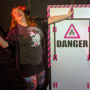 Person posing next to a 'DANGER' sign with a skull and crossbones symbol.
