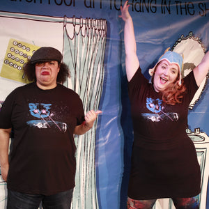 Two people in black t-shirts standing in front of a colorful backdrop with text and images.