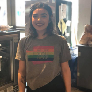 Person wearing a rainbow-themed t-shirt in a kitchen