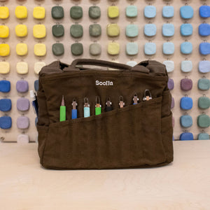 Brown bag with colorful items against a multicolored square patterned wall