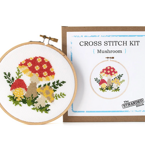 A mushroom cross stitch project completed - sitting next to a box that the project came in.