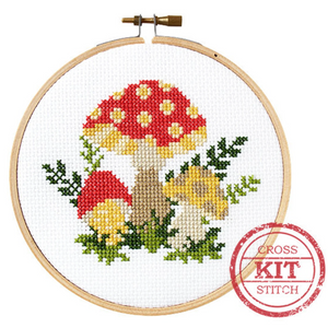 A completed mushroom cross stitch project on a white aida fabric background.