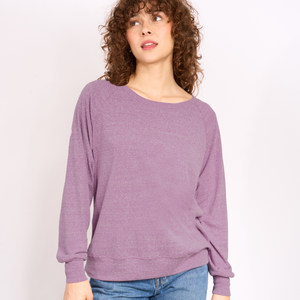 Woman wearing a purple sweater against a white background.