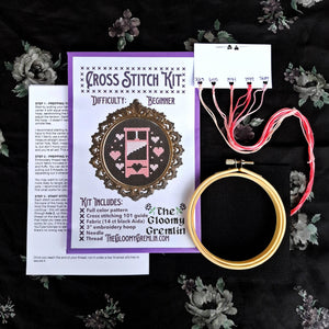 Cross stitch kit with embroidery hoop, thread, and pattern on a dark background