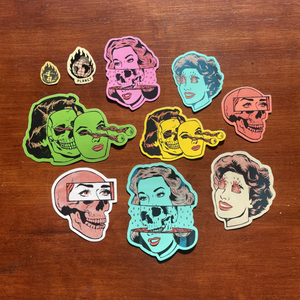 10 stickers of varying sizes and colors depicting cartoon women with fire in their eyes, skulls, and eyeballs shooting out of their heads.