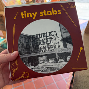 Box packaging for the Tiny Stabs kit of a historic image of the Pike Place Market.