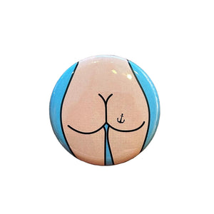 Round button with a design of a butt on a wooden surface