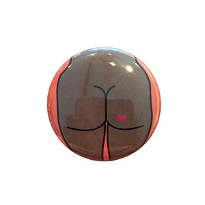 Round magnet with a cartoon illustration of a butt against a white background