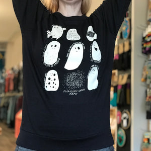 Person wearing a black sweatshirt with white ghost illustrations in a store setting.