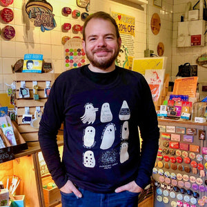 Man wearing a black sweatshirt with white ghost graphics in a store setting.