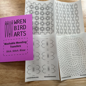 Set of four washable mending transfers from Wren Bird Arts on a wooden surface.