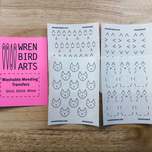 Four variations of cat-themed washable mending transfers from Wren Bird Arts on a wooden surface.