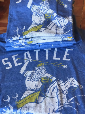 Blue unisex crew t-shirt by Factory 43. It says Seattle and has a mariner wearing a baseball hat and glove and being pulled by two horse mermaids. 