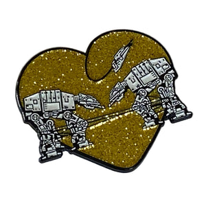 A heart-shaped enamel pin featuring a glittery gold background with white and black line-art illustrations of AT-AT walkers and a Star Wars X-writer flying overhead, set against a white background.