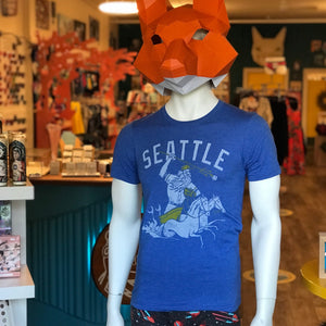 Blue unisex crew t-shirt by Factory 43. It says Seattle and has a mariner wearing a baseball hat and glove and being pulled by two horse mermaids. 