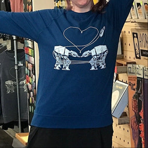 Person wearing a blue sweatshirt with Love AT-AT First Sight design in a store setting