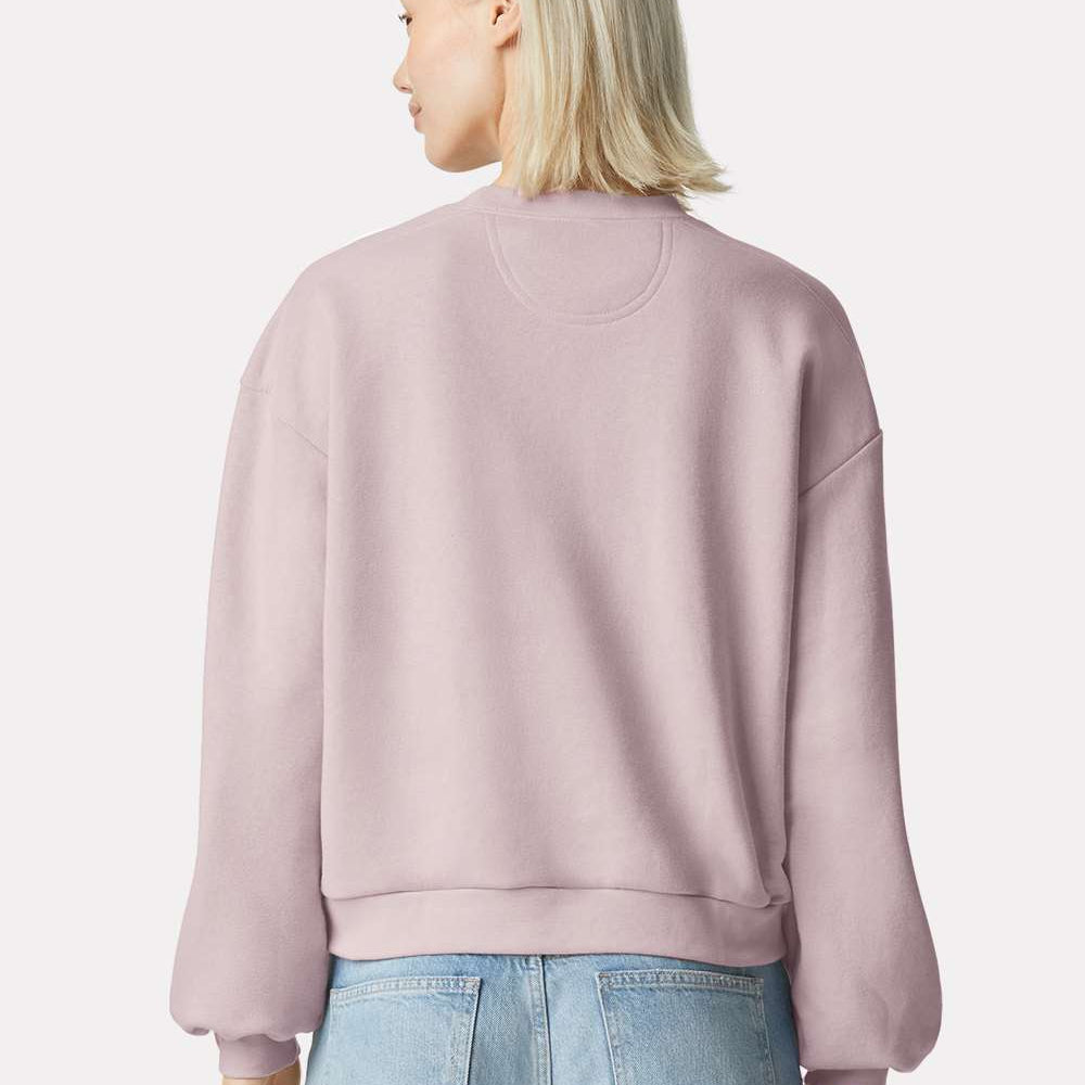 Person wearing a blush pink sweatshirt and light blue jeans on a white background