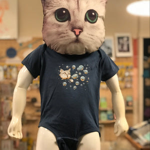Mannequin with a cat head wearing a dark blue baby romper with Ugly Baby's Bubble Cat design in an indoor setting.