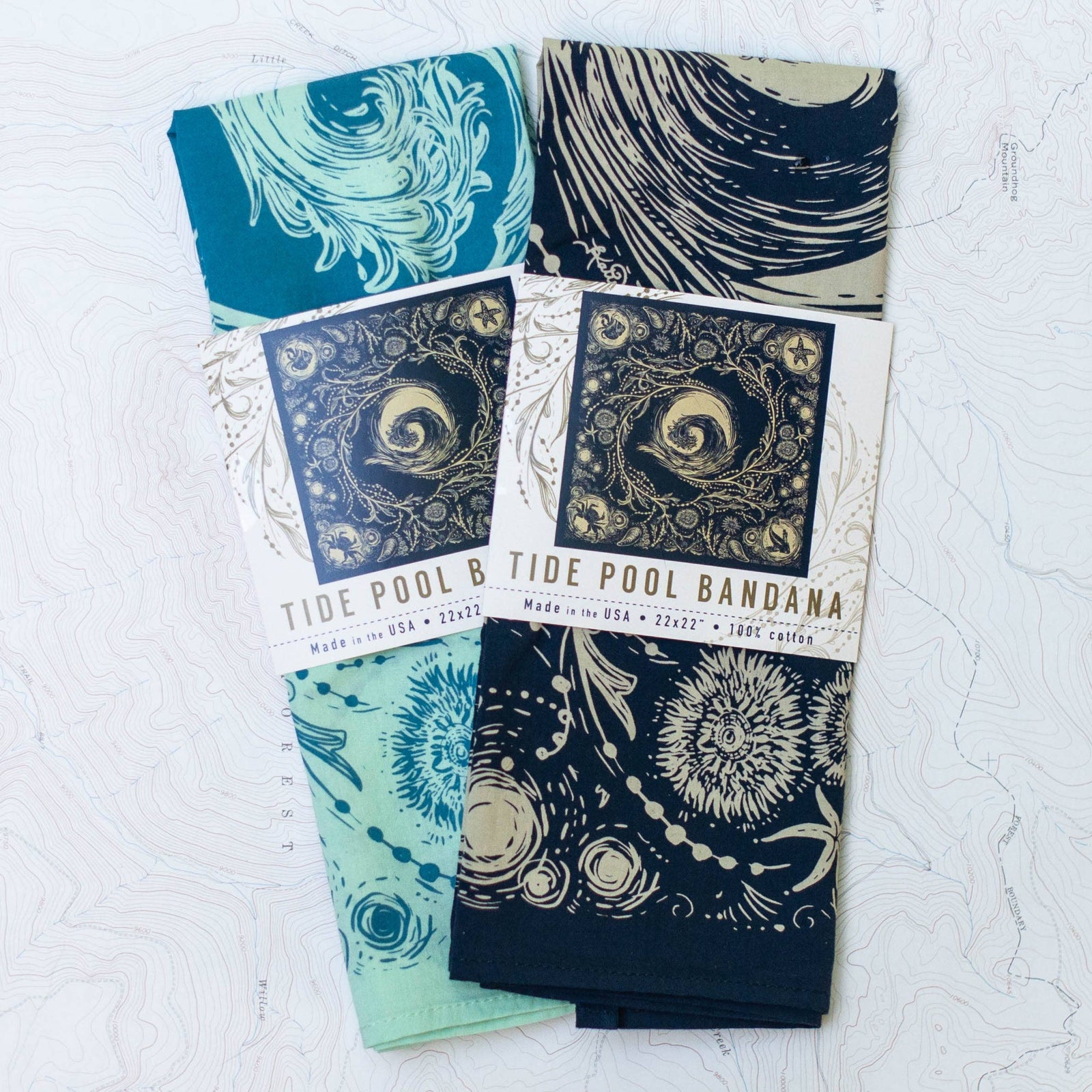 Two patterned bandanas on a textured white surface. 