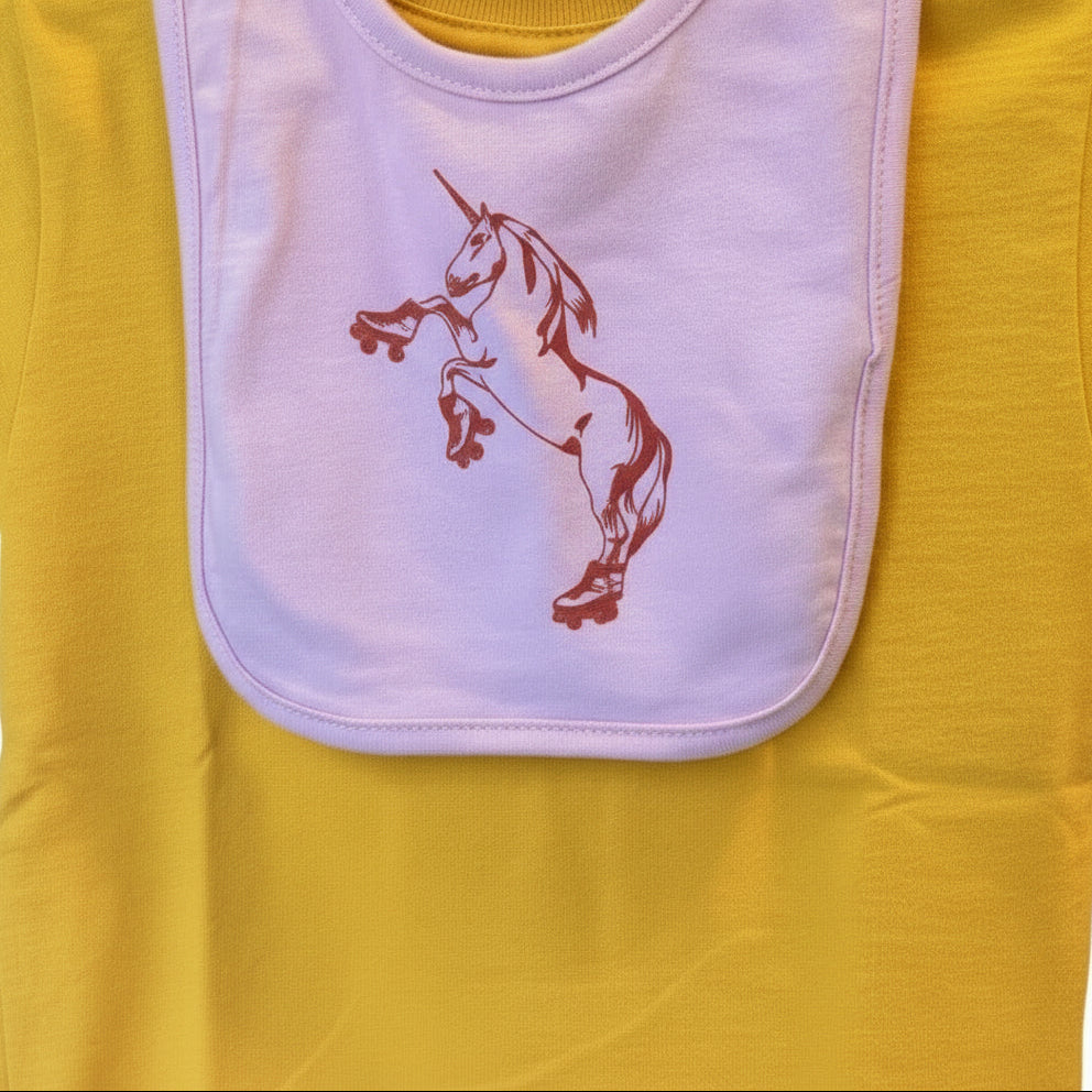 Yellow baby shirt with pink bib featuring a bright red unicorn on roller skates.