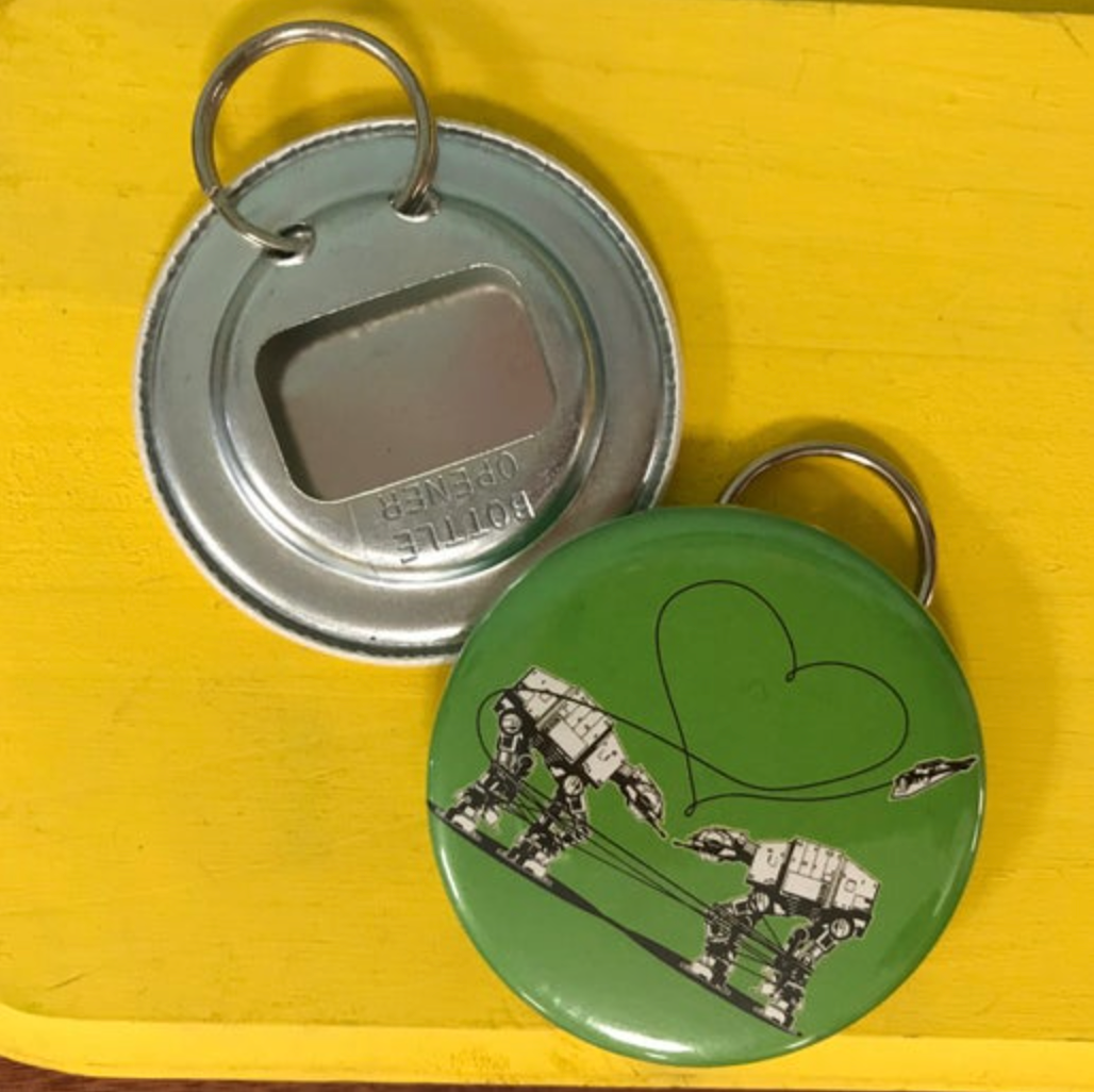 Bottle opener keychain with Love AT-AT First Sight design in green on a yellow background.
