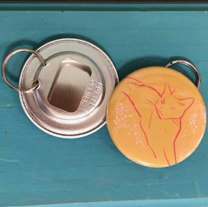Bottle opener with a cat illustration on a blue surface. 