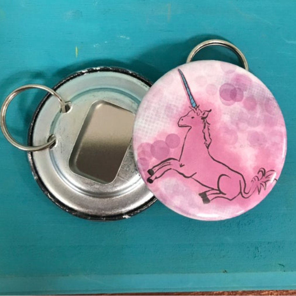 Keychain with tapestry unicorn design and bottle opener on a blue background. 