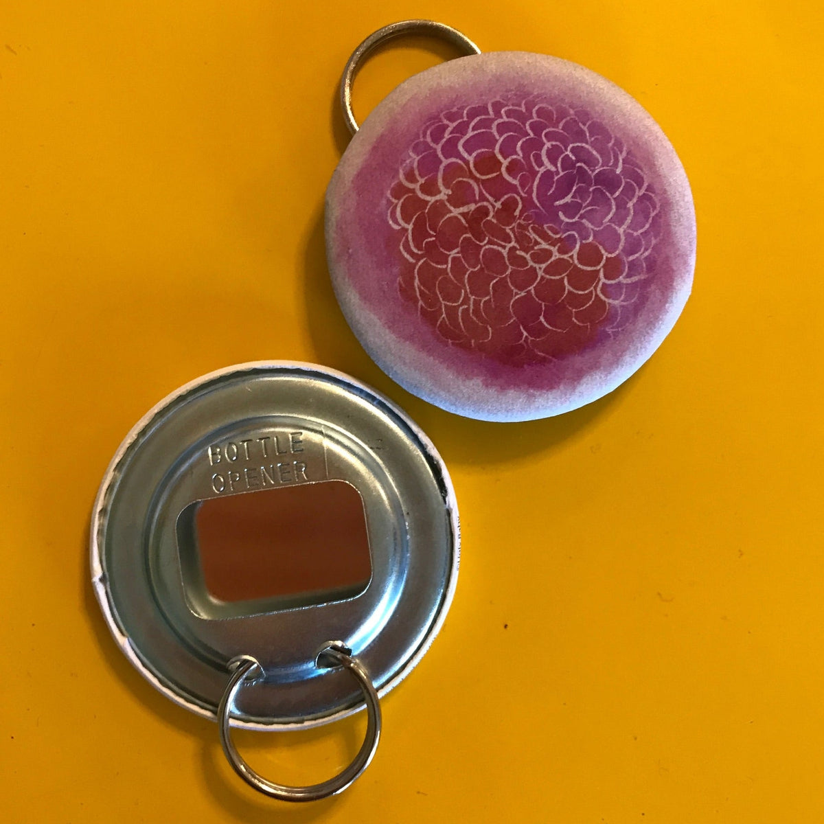 Metal bottle opener and pink watercolor floral on a yellow background. 