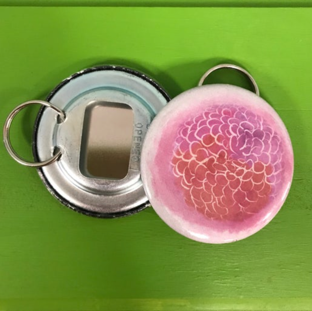 Keychain with bottle opener and pink floral design on a green background
