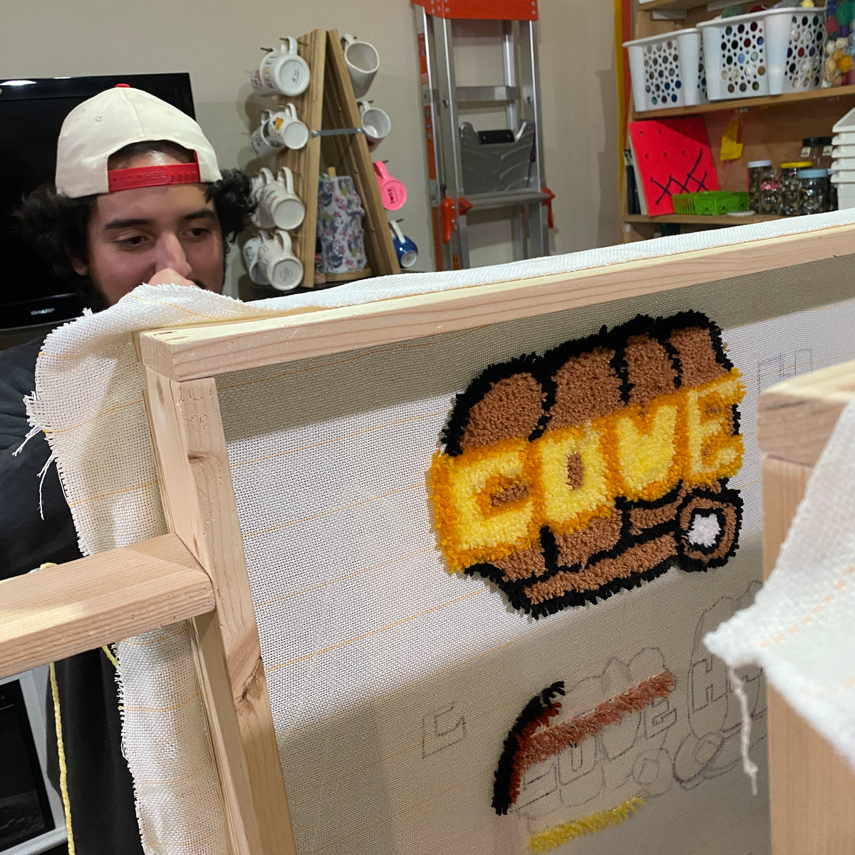 Person holding a tufted art piece in a workshop setting.