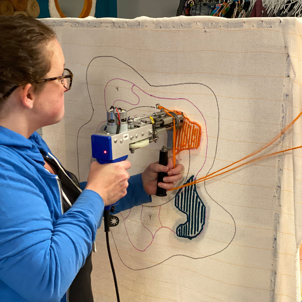 Person operating a tufting machine on fabric. 