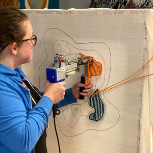 Person operating a tufting machine on fabric. 