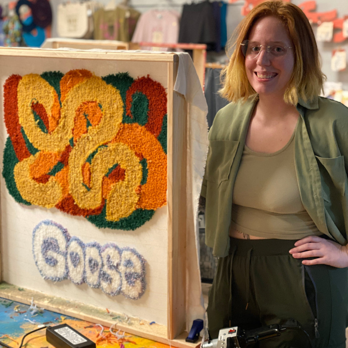 Person standing next to colorful artwork with 'Goose' text at the bottom. 