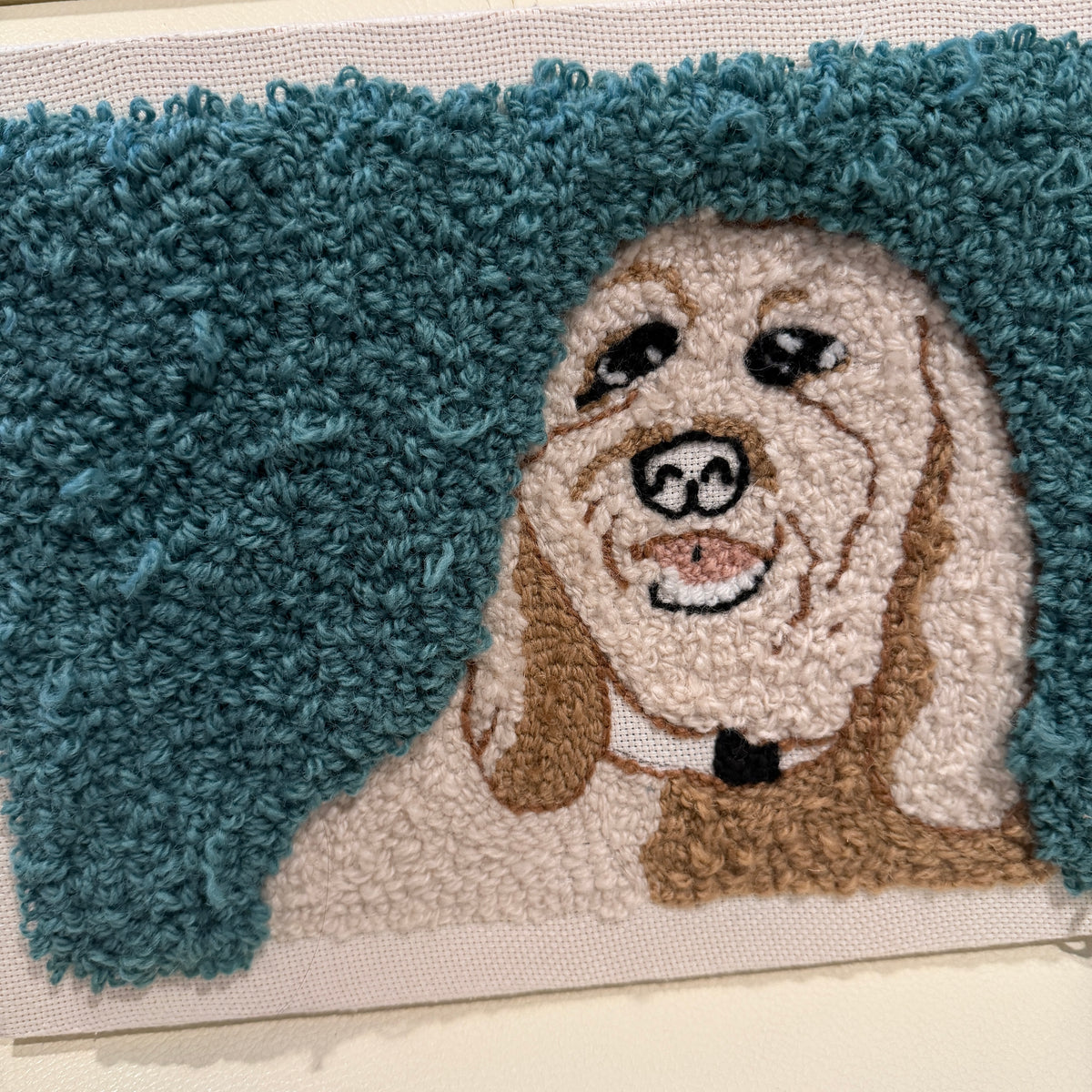 Punch needle wall hanging a dog design on a plain background. 