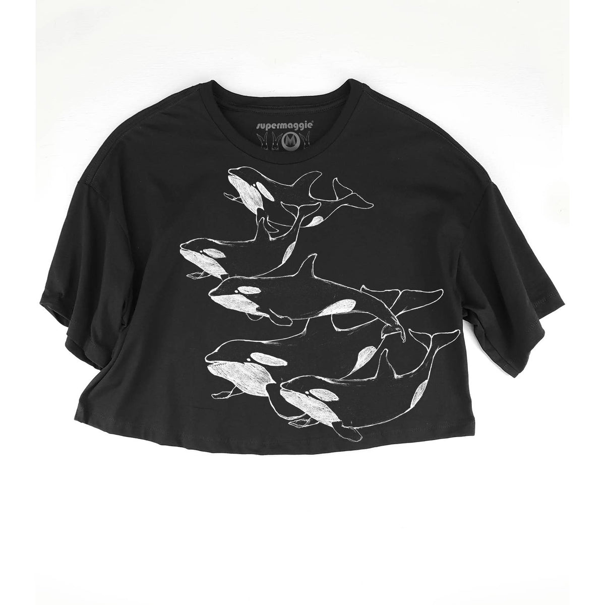 A black short-sleeve crop top t-shirt featuring a white line art graphic of five orcas swimming together across the front. The brand name 'supermaggie' is printed inside the collar.