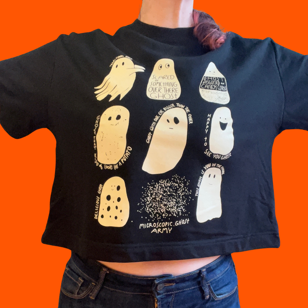 A person wearing a short sleeve, cropped black sweatshirt with illustrations of nine different ghosts screenprinted in cream colored ink. 