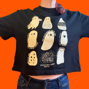 A person wearing a short sleeve, cropped black sweatshirt with illustrations of nine different ghosts screenprinted in cream colored ink. 