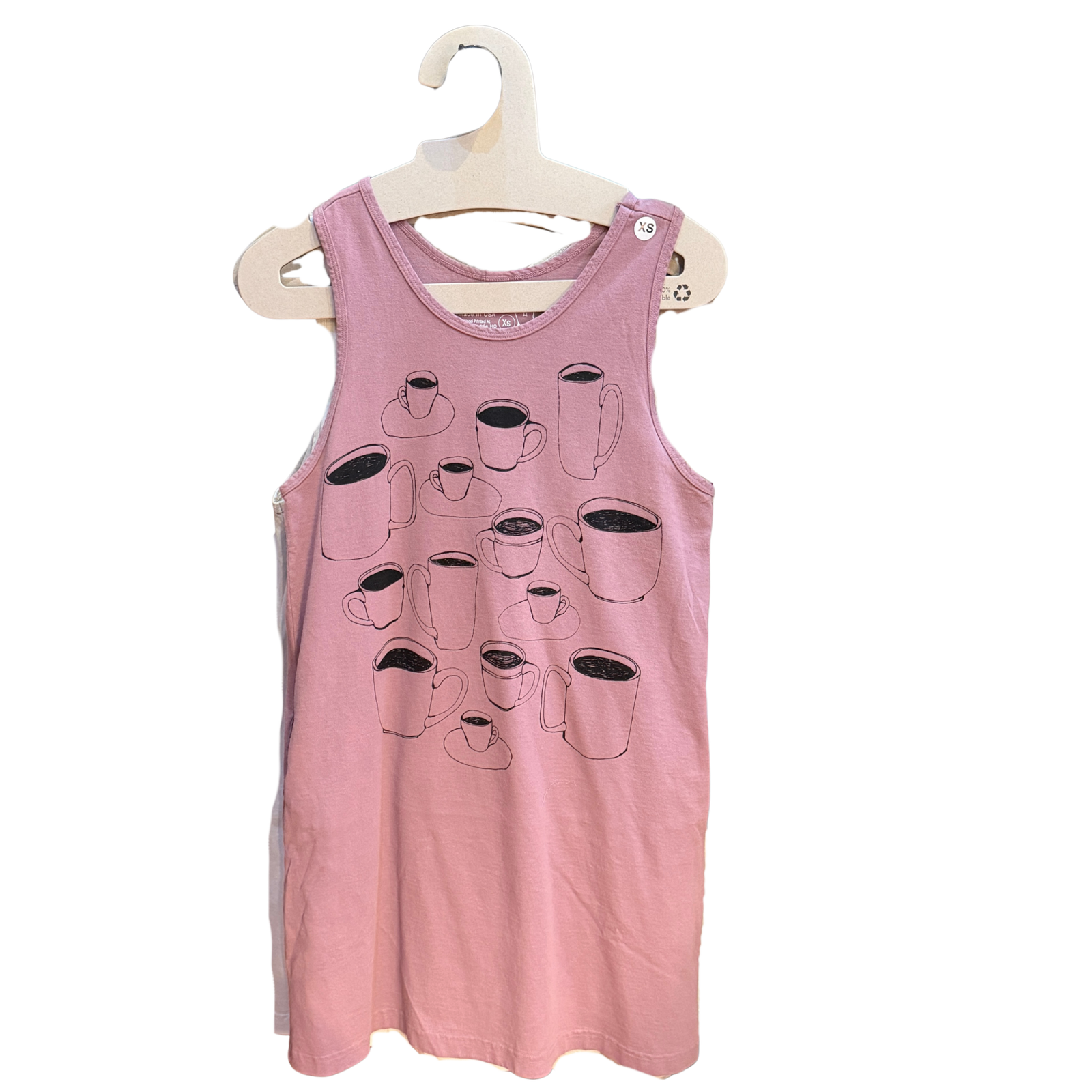 A pink sleeveless tank dress with a graphic print of various coffee cups, hanging on a hanger against a plain white background.