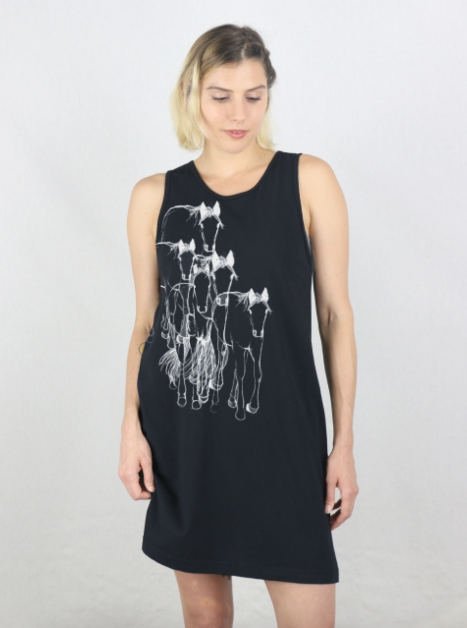 Woman wearing a black sleeveless dress with white horse illustrations on a plain background. 