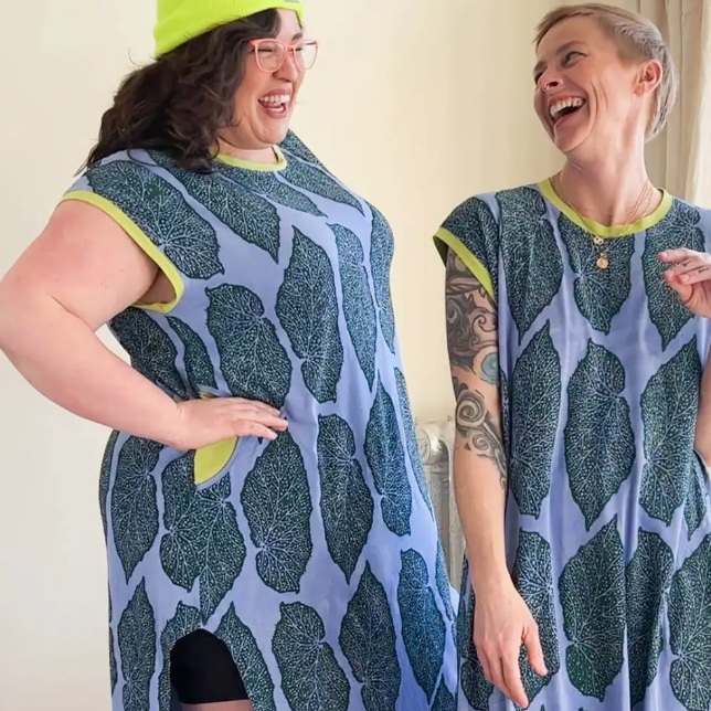 Two people wearing matching patterned dresses with a plain background.