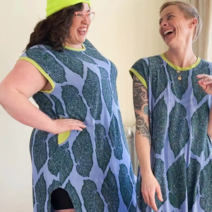 Two people wearing matching patterned dresses with a plain background.