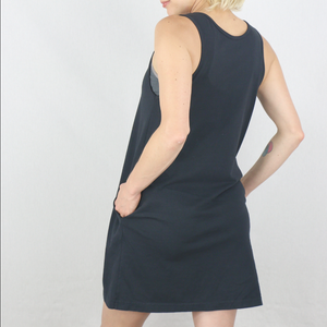 Person wearing a black sleeveless dress against a white background. 