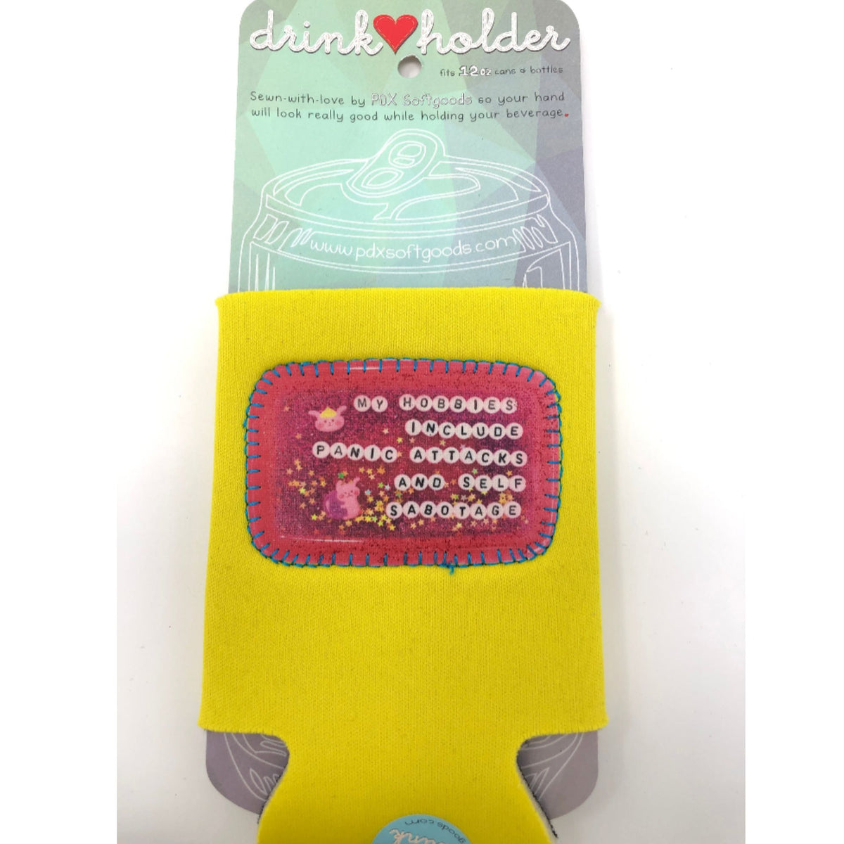 Yellow drink holder with pink patch on a white background. It says "My hobbies include panic attacks and self sabotage."