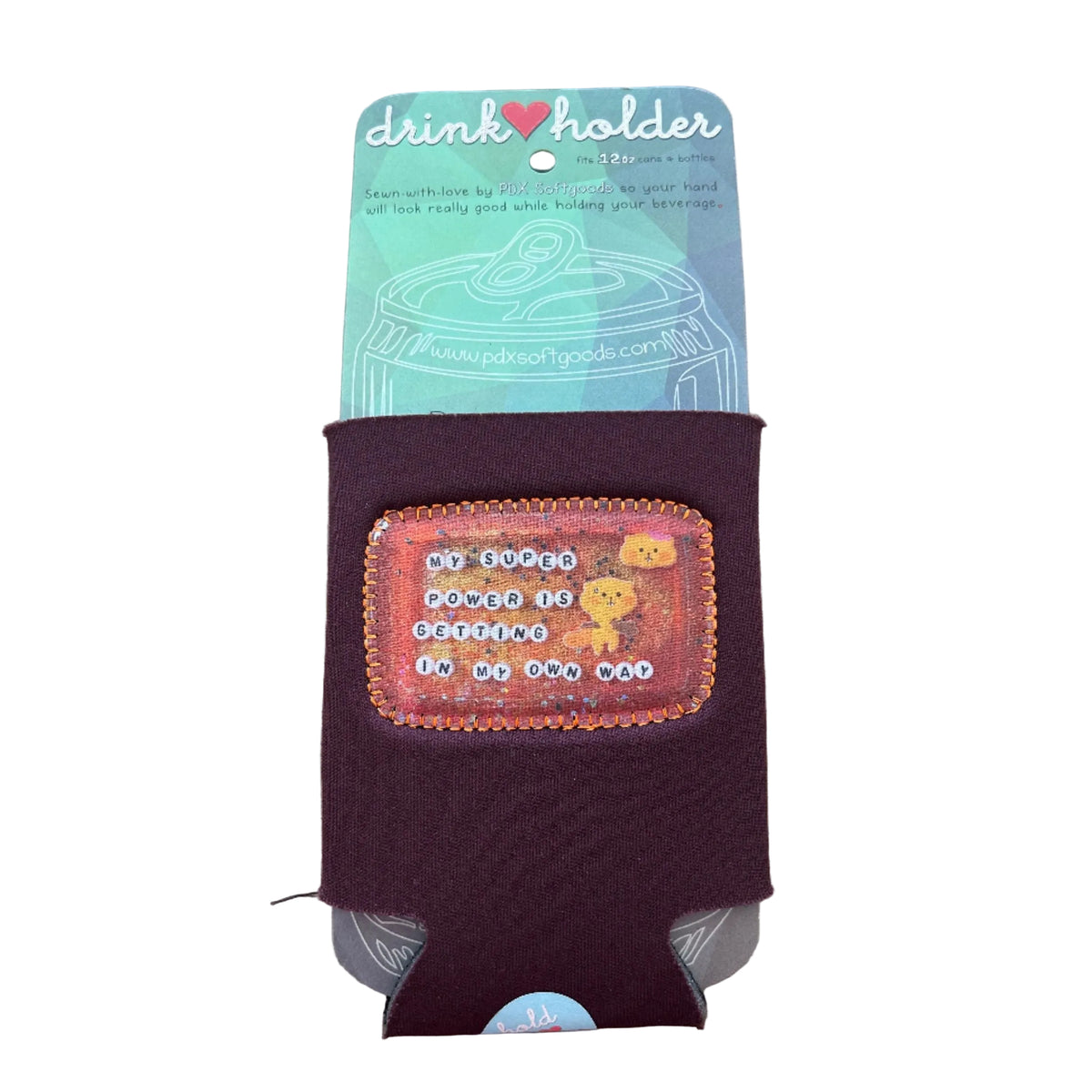 Maroon drink holder with a colorful patch on a wooden surface. The patch says "My super power is getting in my own way." 