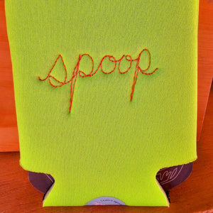 A bright lime green neoprene can cooler sleeve with the word 'spoop' embroidered in orange-  shown on a wooden surface.