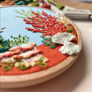 Embroidery hoop with a colorful underwater scene including coral and fish.