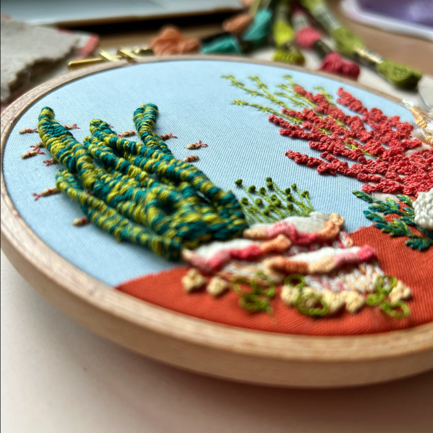 Embroidery hoop with colorful floral design on a light background. 